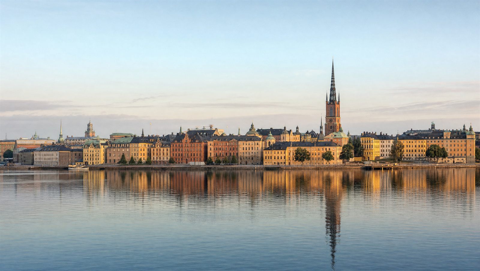 Gamla stans färgade fasader speglas i vattnet en morgon i Stockholm